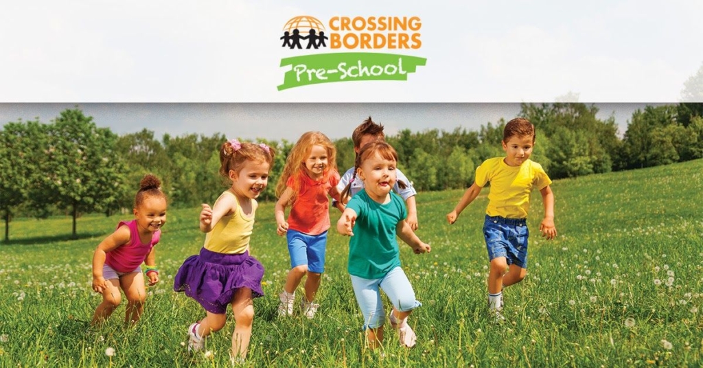 A group of preschoolers runs joyfully through a grassy field, celebrating playfulness and fun in the sun.