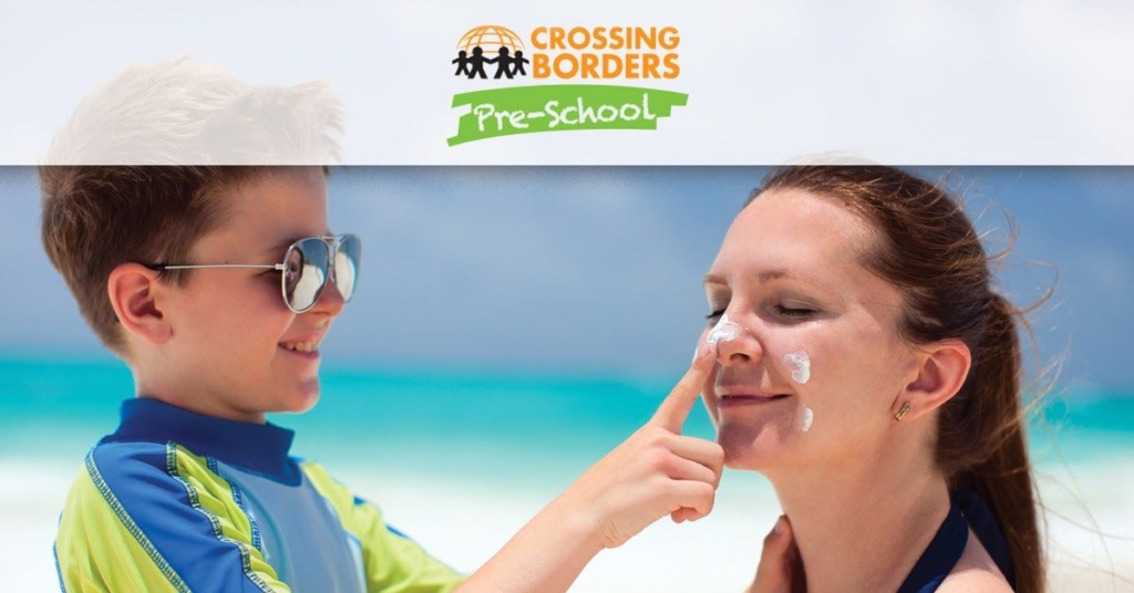 A child playfully applies sunscreen to his maother's nose at the beach, highlighting fun and care in a sunny environment.