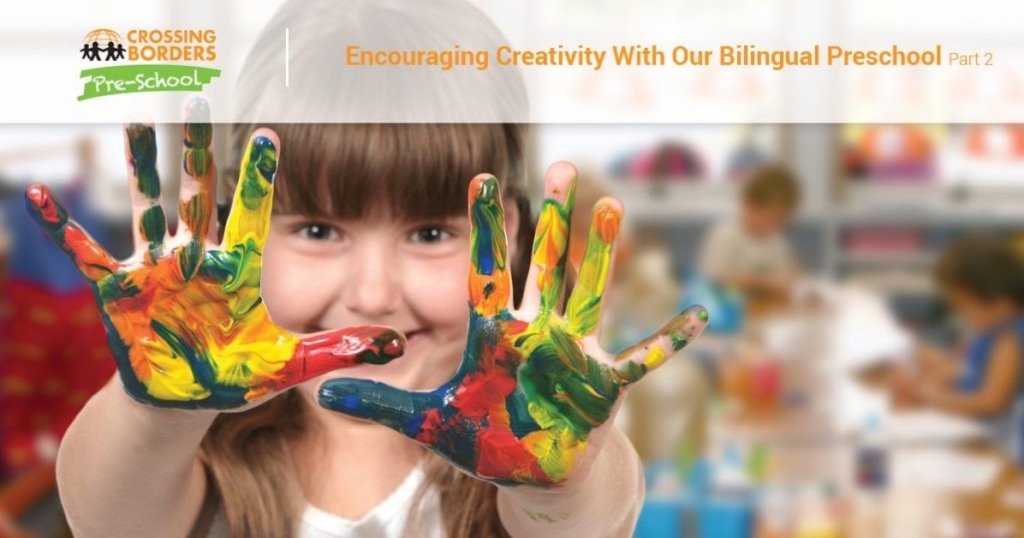 A girl proudly shows her colorful, paint-covered hands, celebrating creativity in a vibrant preschool environment.