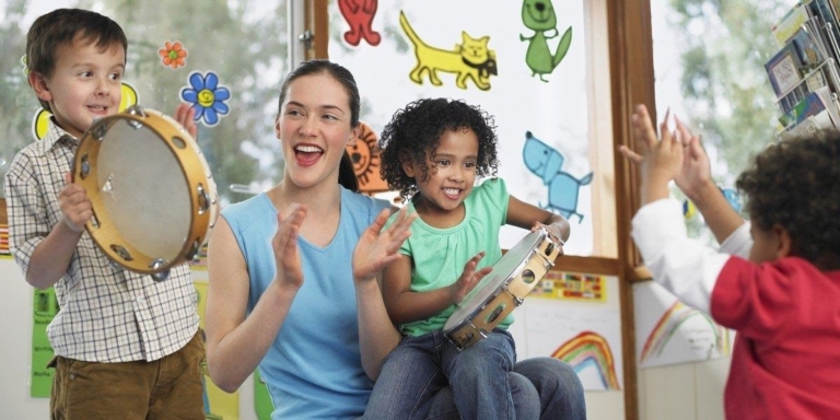 A joyful music class where children play tambourines, led by a smiling teacher, encouraging rhythm and participation.