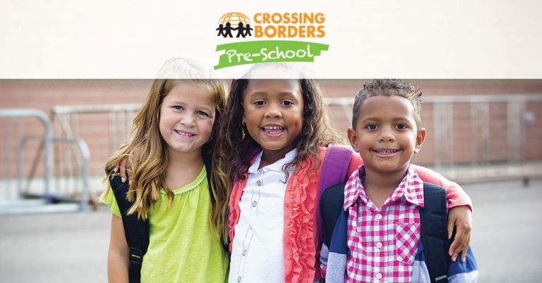 Three smiling preschoolers pose together with backpacks, radiating friendship and excitement for their school day.