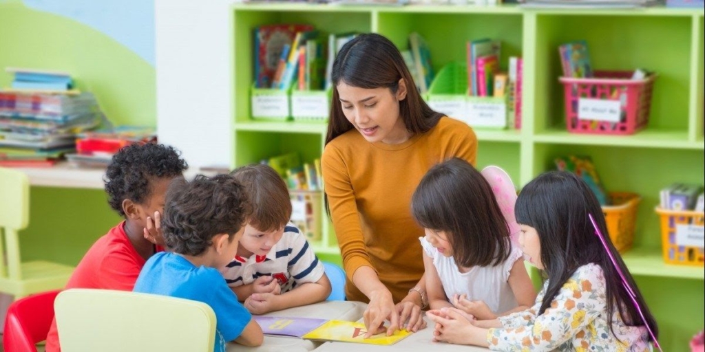 A teacher guides a group of children in a hands-on learning activity at a table, promoting collaboration and engagement.