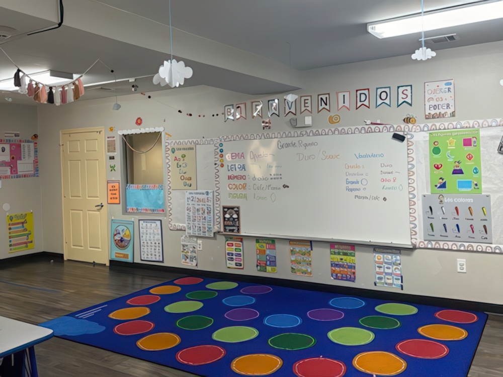 A bright classroom features small tables and chairs and walls adorned with classroom decorations designed for preschoolers.