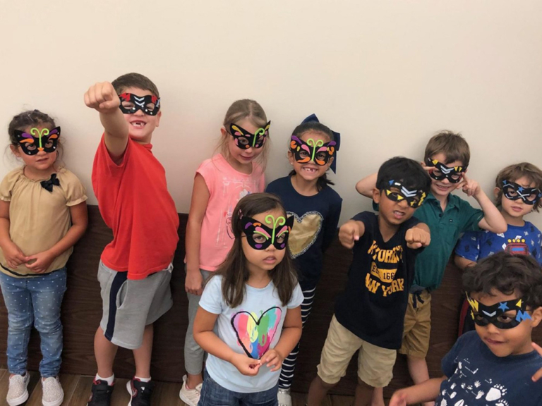 A group of children wearing colorful masks strike fun poses, showing excitement and camaraderie in a playful setting.